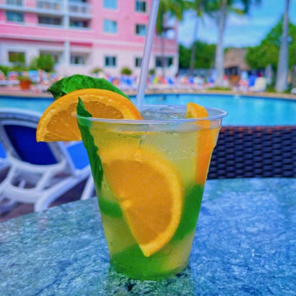 A refreshing cocktail with orange slices and mint, poolside at The Islander Grill and Tiki Bar.
